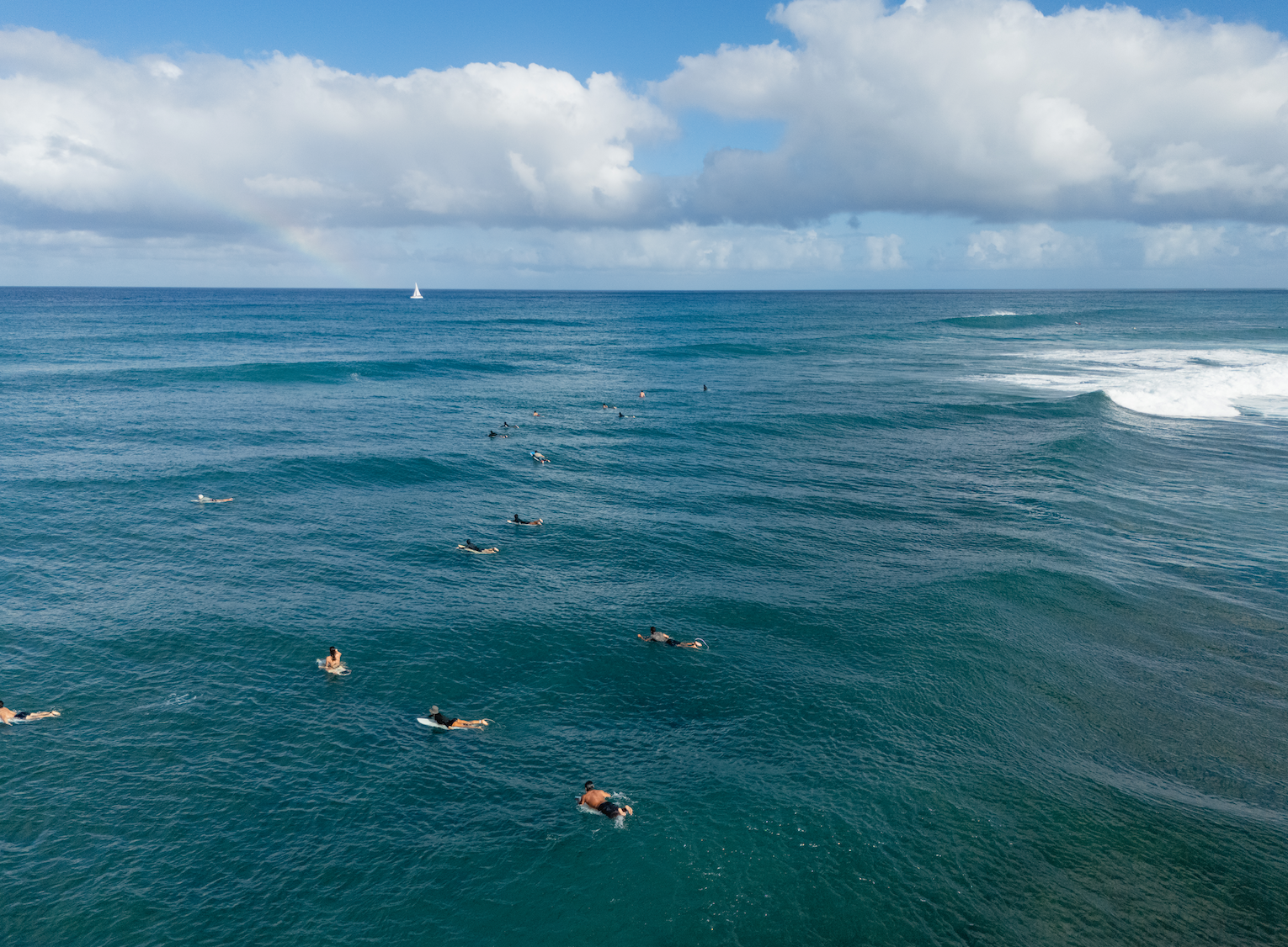 Surfers paddling out on north shore surf spot, Laniakeas